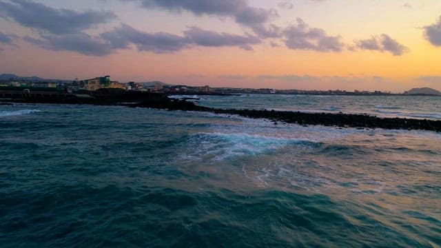 Coastal View at Dusk with Waves and Cityscape