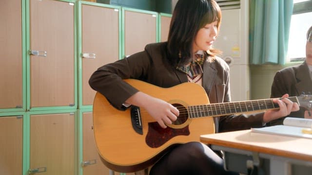 Student playing guitar in a classroom