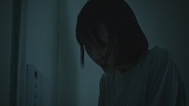 Woman breathing through an inhaler for asthma in a dark room