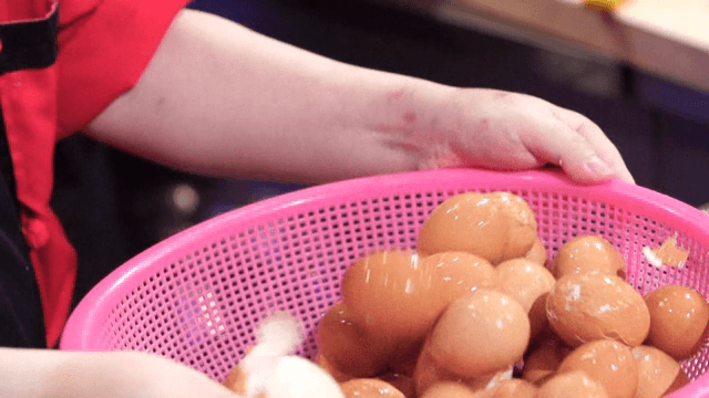 Boiled eggs being peeled in a colander