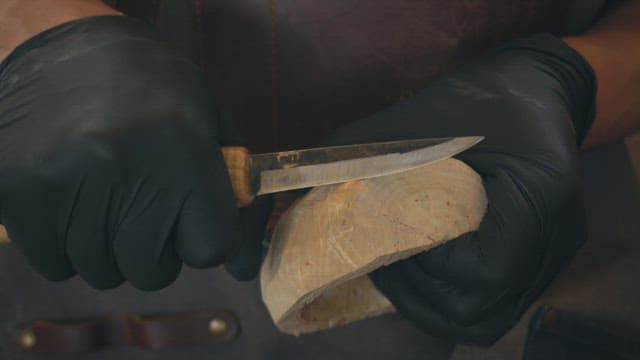 Hands carving wood with a knife