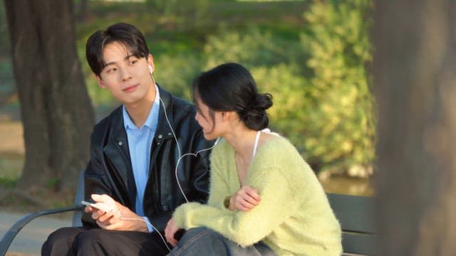 Couple sharing earphones on a park bench