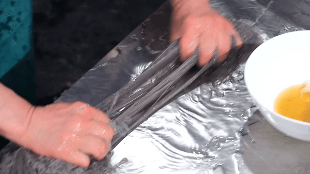 Chef preparing cold buckwheat noodles on a metal surface
