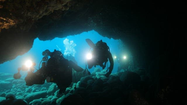 Scuba Divers Exploring Underwater Cave