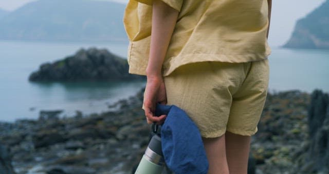 Back View of a Person Standing on a Windy Rocky Coast