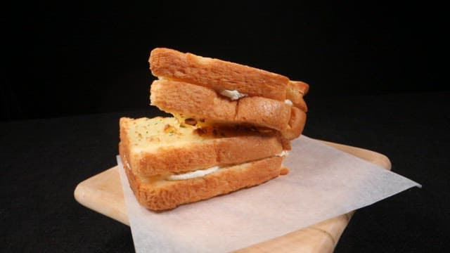 Garlic bread slices filled with cream on a wooden board