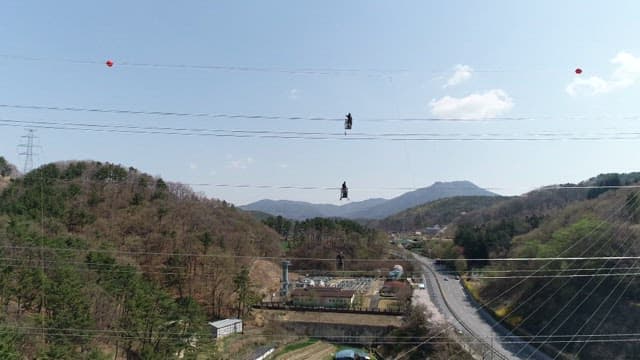 Workers hanging from power lines to inspect transmission towers in mountainous areas