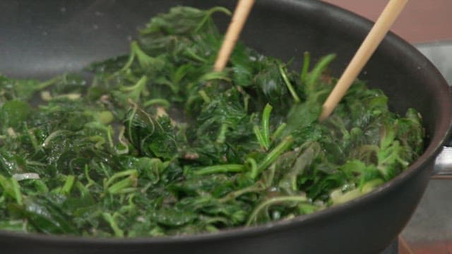 Stir-frying perilla leaves in a pan with chopsticks