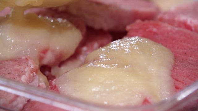 Pouring the sauce over the pork seasoned with pepper