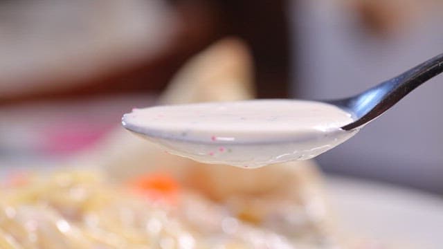 Creamy sauce being poured over pasta