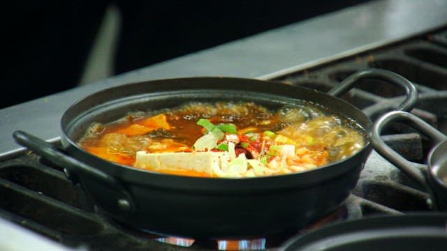 Mustard leaf kimchi stew boiling in a restaurant kitchen