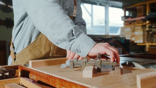 Craftsman Measuring Wood in Workshop