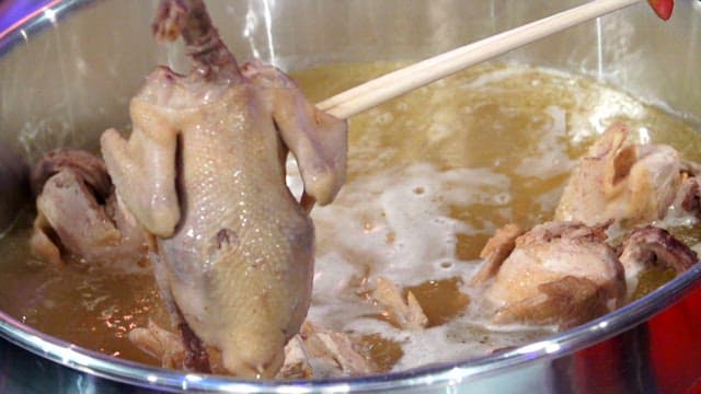Piece of chicken pulled out of a big pot