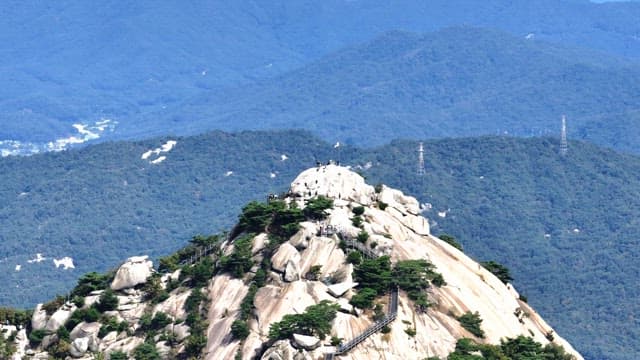 Buramsan mountain peak with hikers and a flag