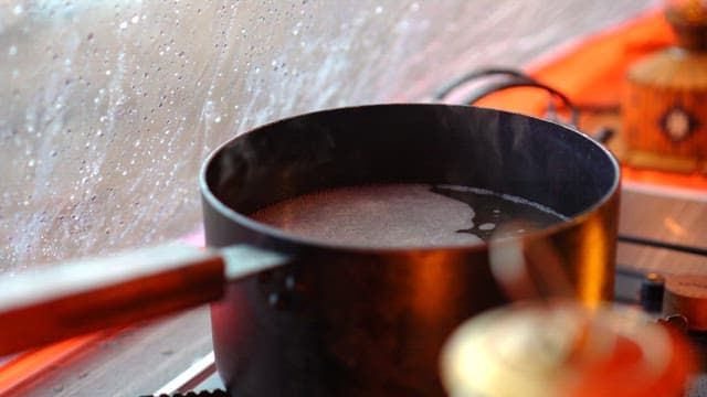 Putting vegetables into a pot for cooking in a tent on a rainy day