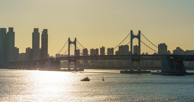 From morning to night view of a bustling port city Busan with tall skyscrapers and Gwangan Bridge