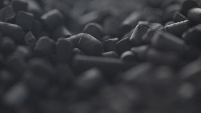 Close-up view of dark, textured mineral pellets.