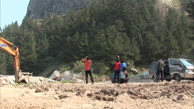 People Surveying a Mountainous Construction Site