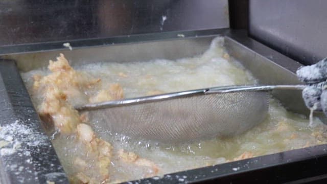 Meat being fried in a fryer in a restaurant kitchen