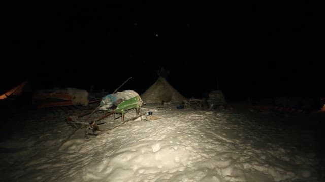 Snow-covered campsite with tents at night
