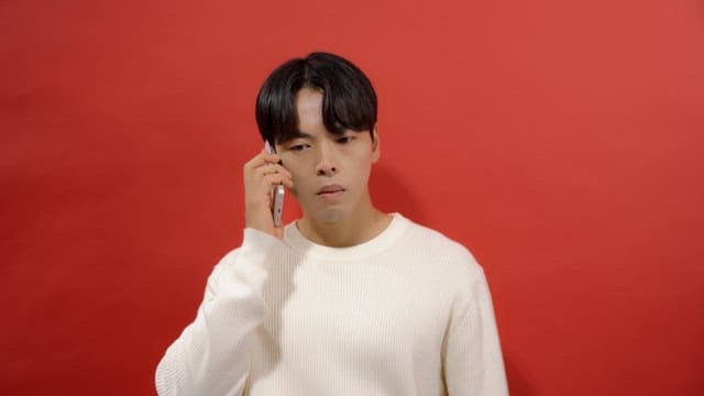 Man in white sweater talking on cell phone and getting angry