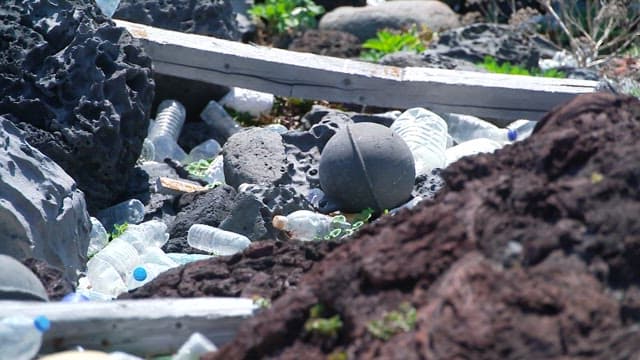 Rocky coastal area littered with various types of waste