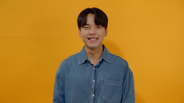 Man in denim shirt smiling brightly, expressing joy