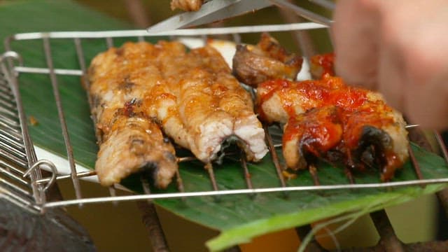 Grilled eel being prepared on a barbecue