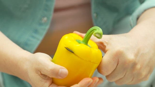 Hands preparing a yellow bell peppers