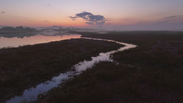 Calm river at sunset with a bridge