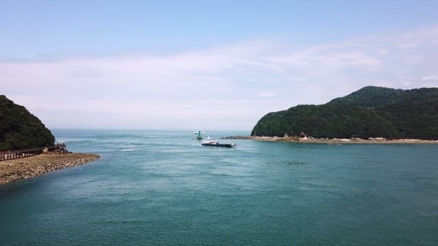 Tugboat sailing on a calm sea with an island in sight