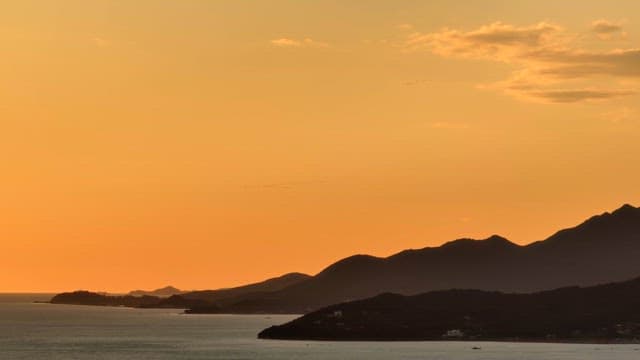 Sunset over the ocean with distant mountains