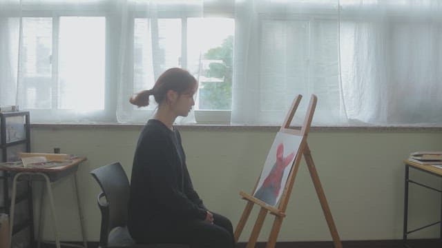 Woman looking at a painting on an easel in an art room