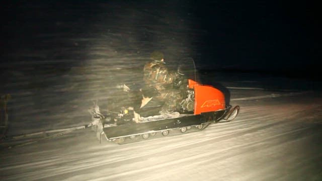 Snowmobile Journey Through a Snowy Terrain at Night