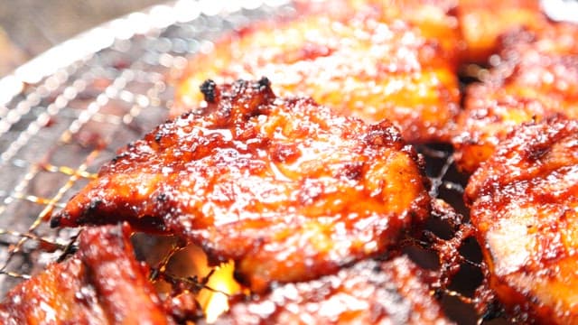 Seasoned meat sizzling on a grill over blazing charcoal