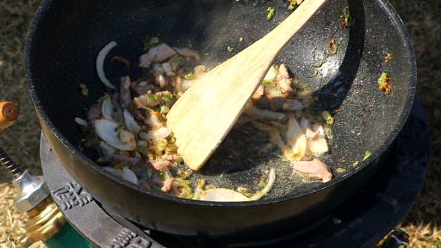 Stir-frying green onions, garlic, and minced pork in a pan