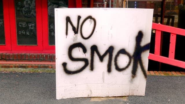 No smoking sign in front of a red building