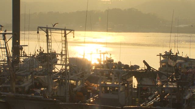 Fishing boats on the sea reflected in the sunrise