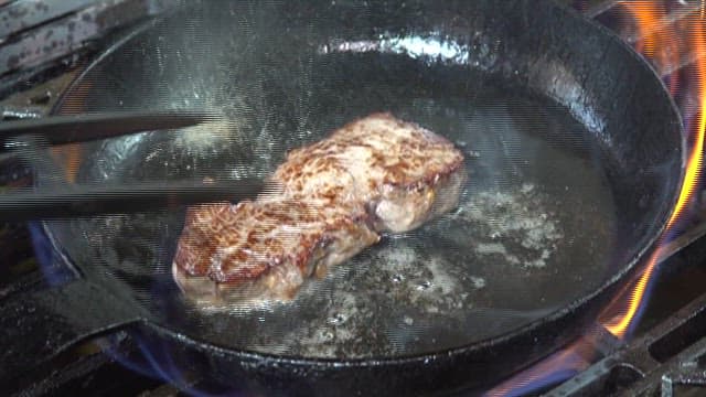 Sizzling beef steak on a flaming grill pan