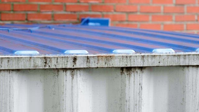 Raindrop falling on corrugated metal roof with rust of conatiner building