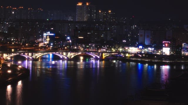 Night view of a brightly lit urban bridge reflecting on the river