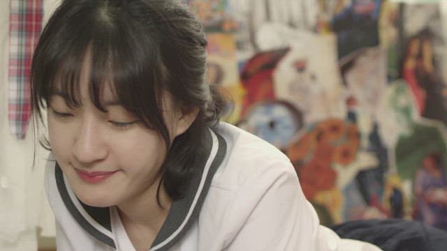 Female student lying face down in a room with colorful wallpaper