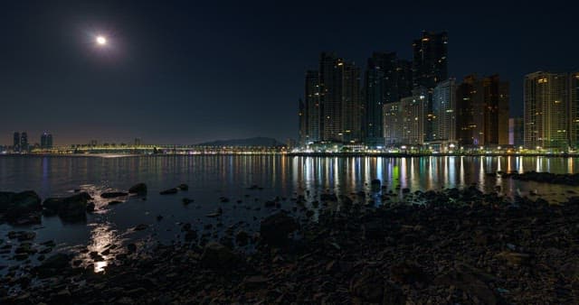 Cityscape from night to dawn with buildings and quiet beach