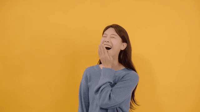Long haired woman laughing joyfully and happy in gray sweater