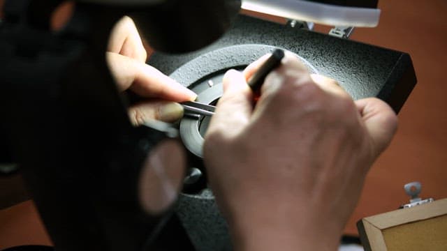 Working on a red gemstone under bright lights