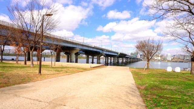 Winter scenery of riverside park and bridge under blue sky