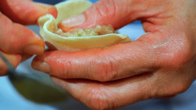 Close-up of hands preparing dumplings