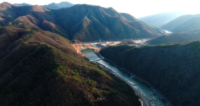 Mountain Village by the River with Suspension Bridge