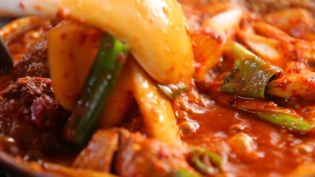 Mixing the spicy braised ribs with plenty of vegetables using a spoon