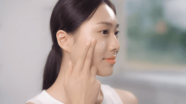 Woman applying facial cream in a well-lit room
